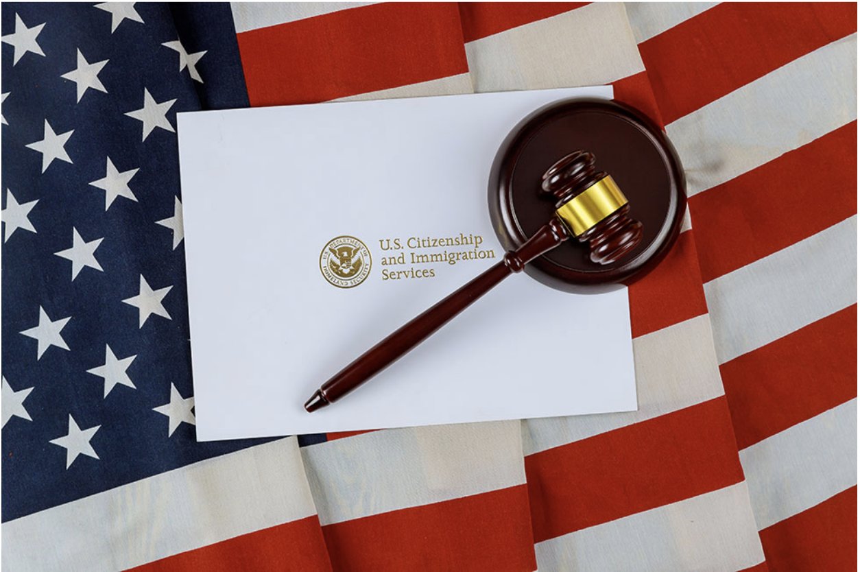 Judge’s gavel, US Citizenship and immigration services envelope on a US flag